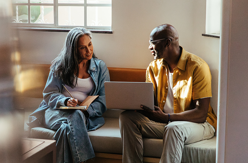 Teammates collaborating on a project using a laptop.