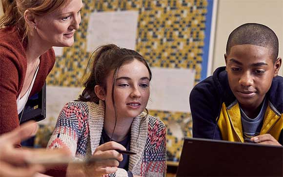 Student using laptop with teacher