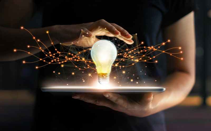 woman holdng a lightbulb over a tablet